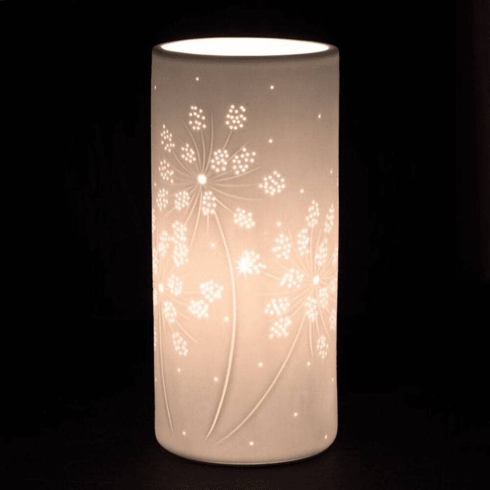 Lampe blanche en forme de cylindre avec des motifs de fleurs sur fond noir