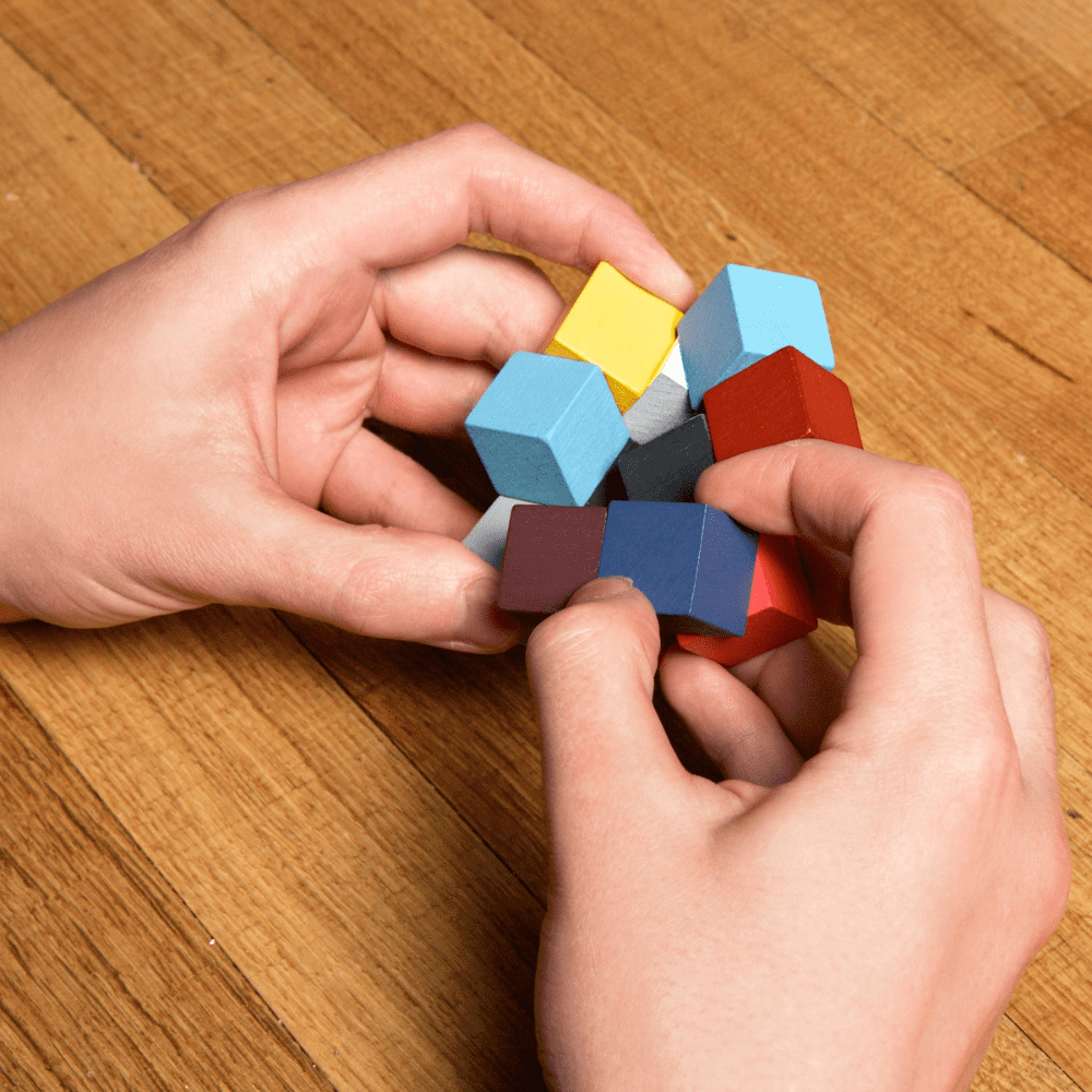 mise en situation personne qui joue au puzzle 3D sur table en bois