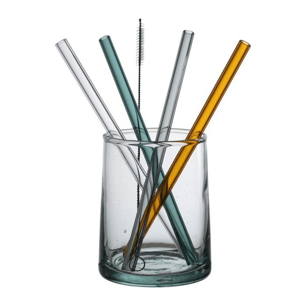 4 pailles multicolores et brosse dans un verre sur fond blanc