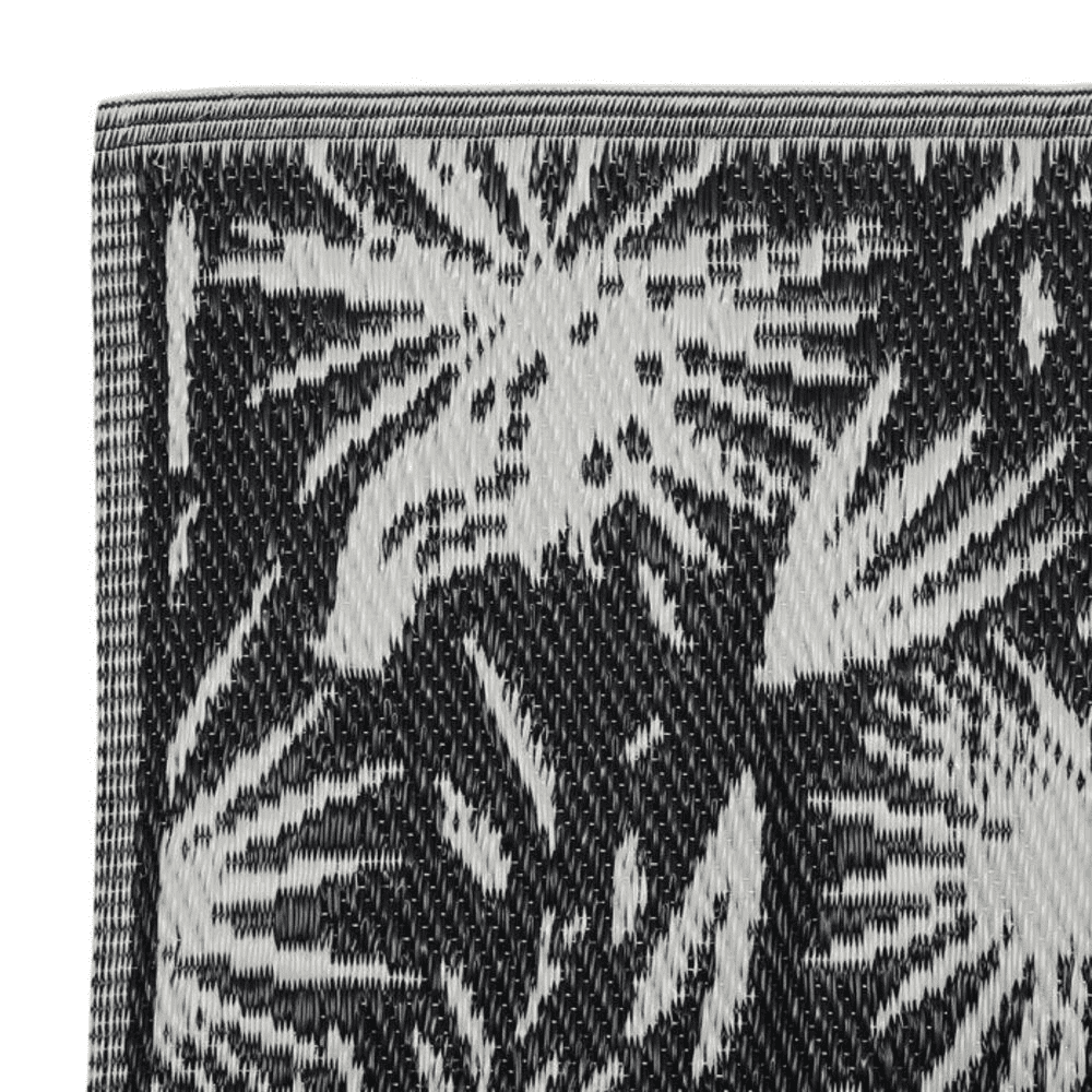 Tapis plié noir et écru avec des motifs sur fond blanc